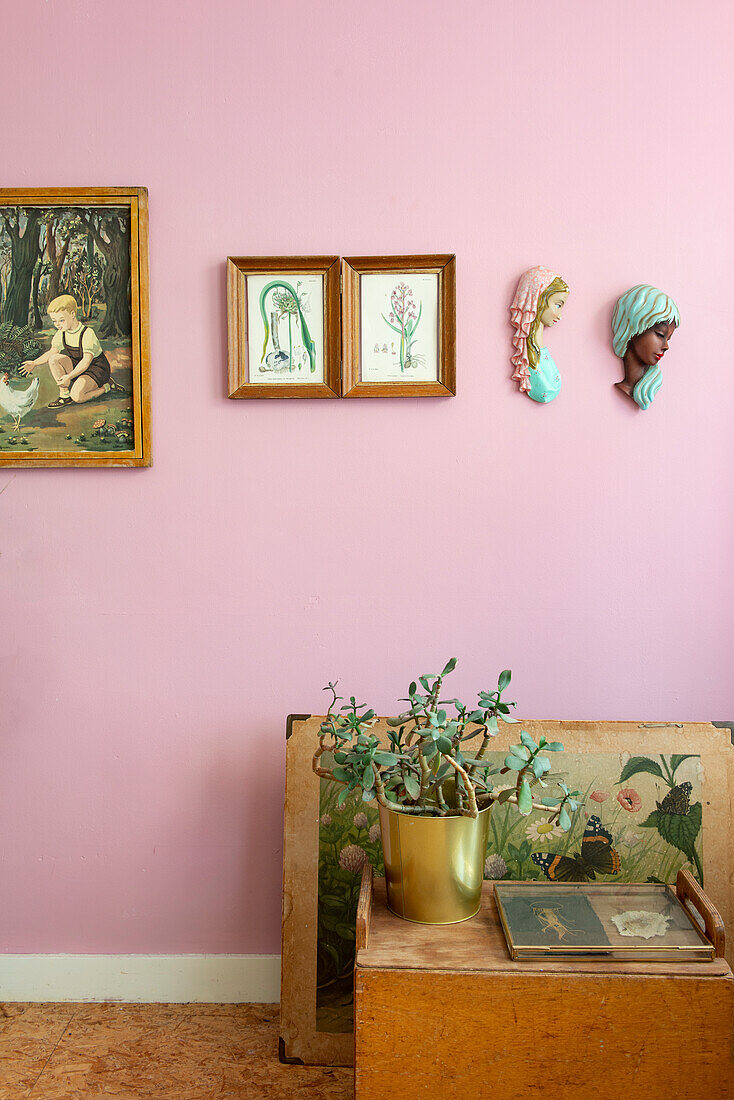 Vintage pictures and wall busts on a pink-colored wall