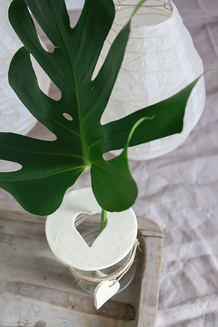 Decorative monstera leaf in glass vase on wooden table