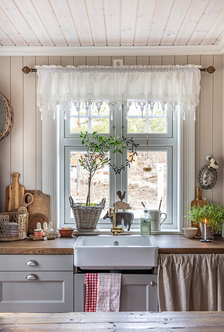 Landhausküche mit Spülbecken unter Fenster und rustikaler Dekoration