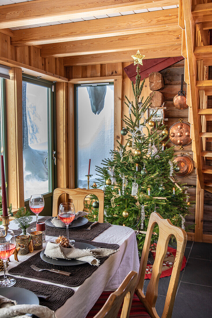 Weihnachtlich gedeckter Esstisch mit Tannenbaum in Holzhaus