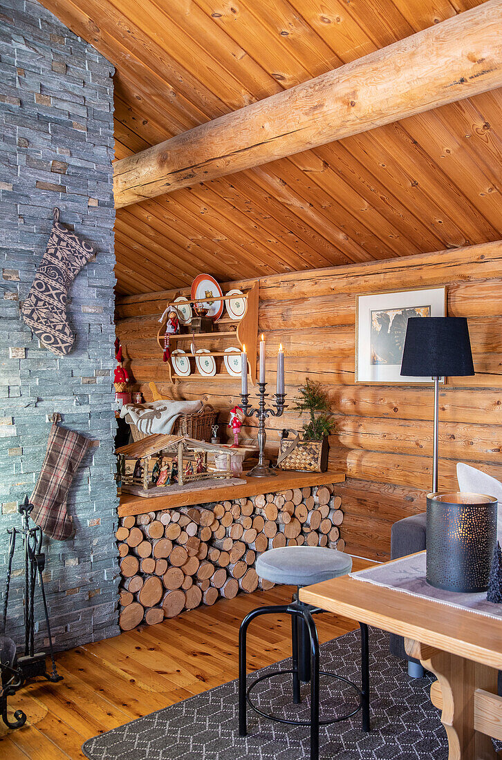 Holzverkleidetes Wohnzimmer mit Kaminholz-Lager und Klinkerwand