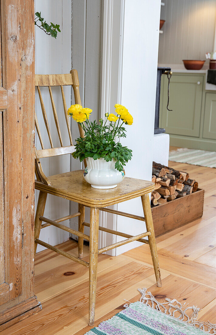 Gelbe Blumen in weißer Vase auf Holzstuhl