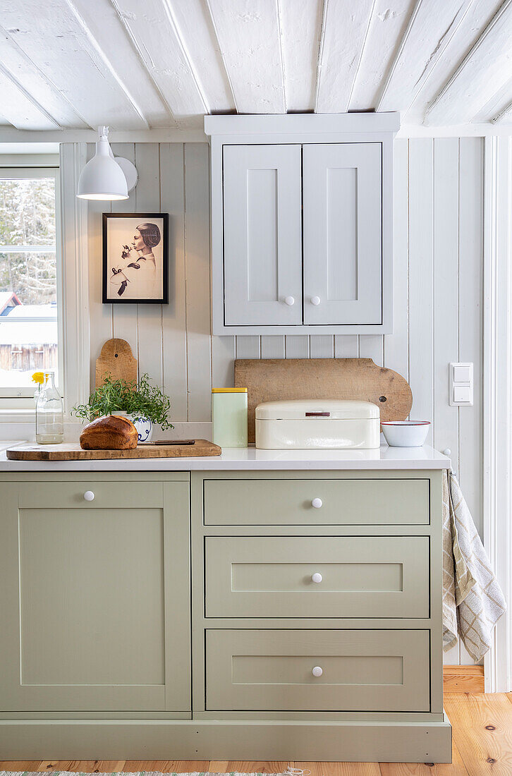 Country-style kitchen with green cupboards, grey wall unit and white ceiling lamp