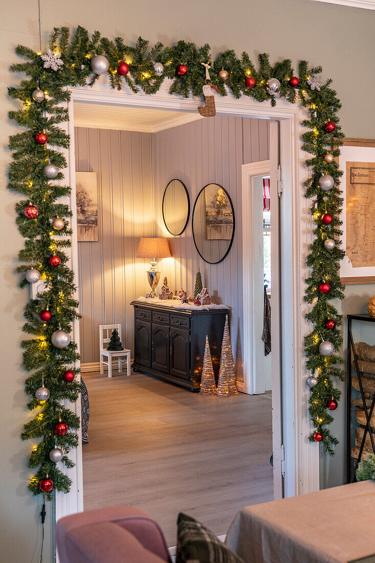 Door frame decorated for Christmas with garland and lights