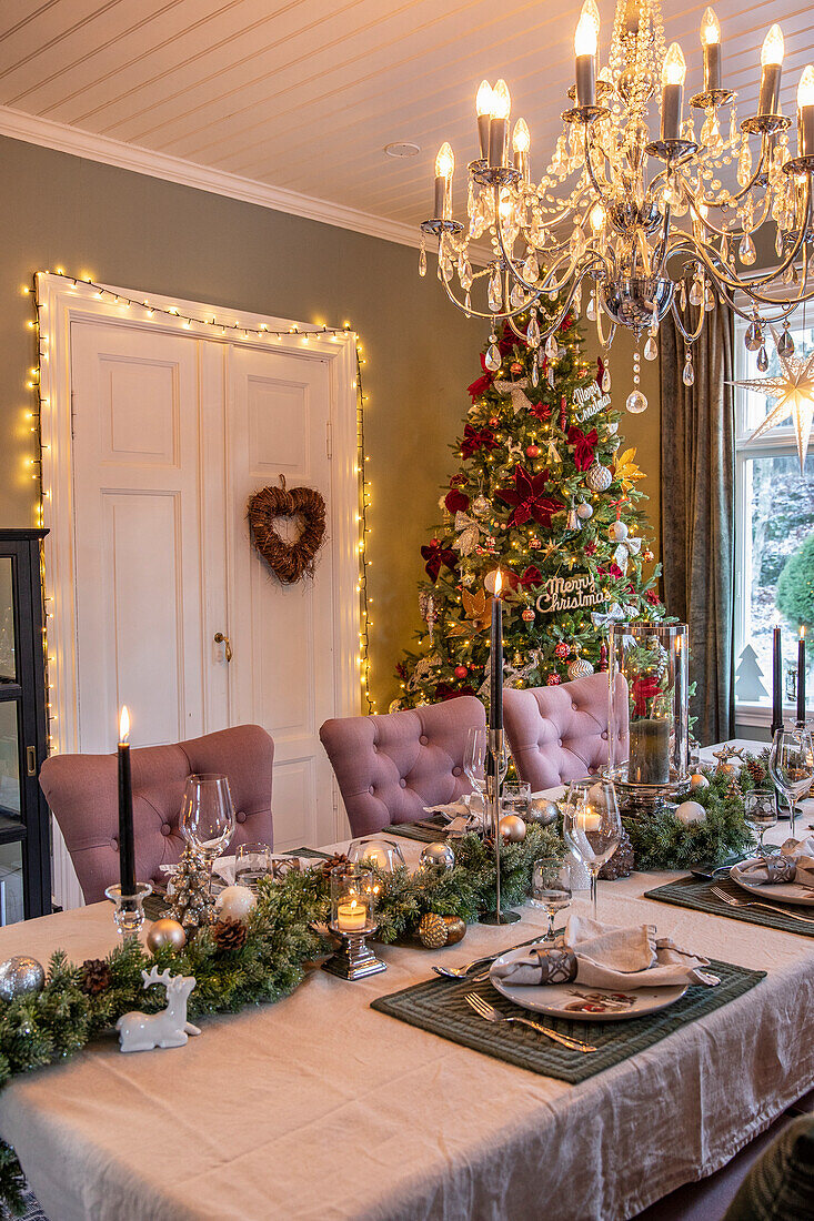Festively decorated dining area with Christmas tree and chandelier