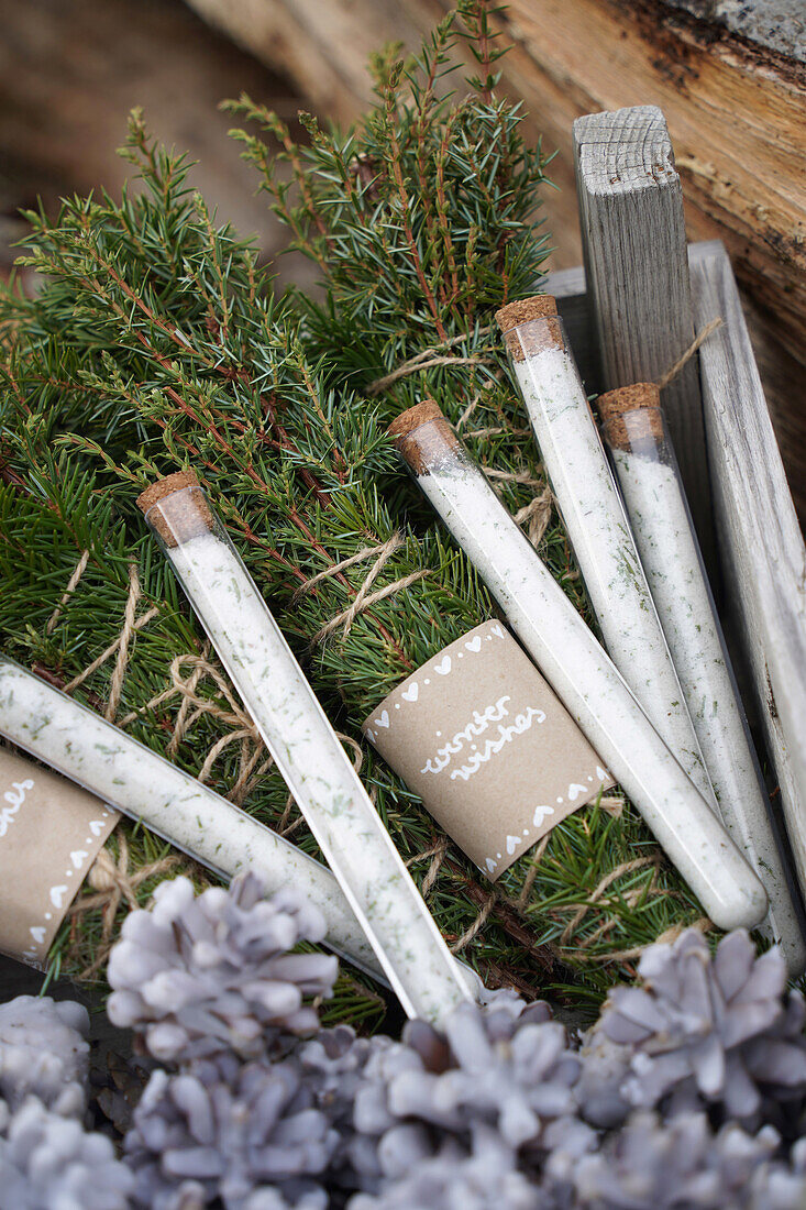 Wooden box with cone fire starters, bundle of incense made from juniper and spruce branches, spruce salt in test tubes, DIY