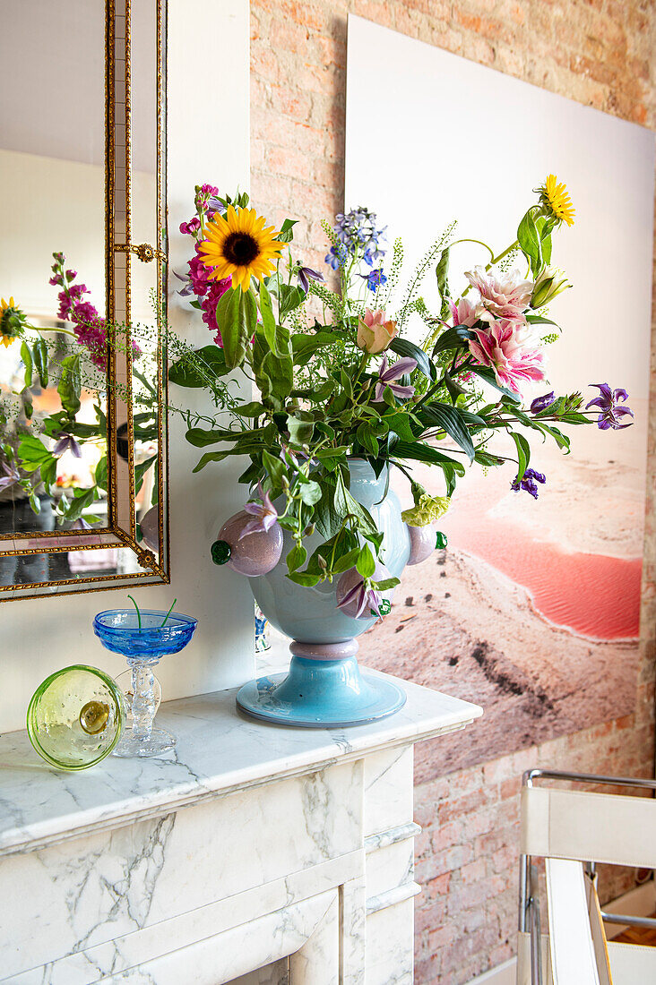 Colorful bouquet of flowers in blue vase on mantelpiece