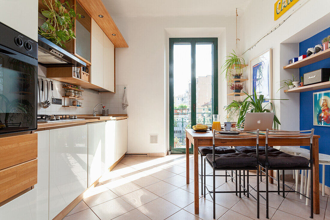 Helle Küche mit Holzelementen und Essplatz am Fenster