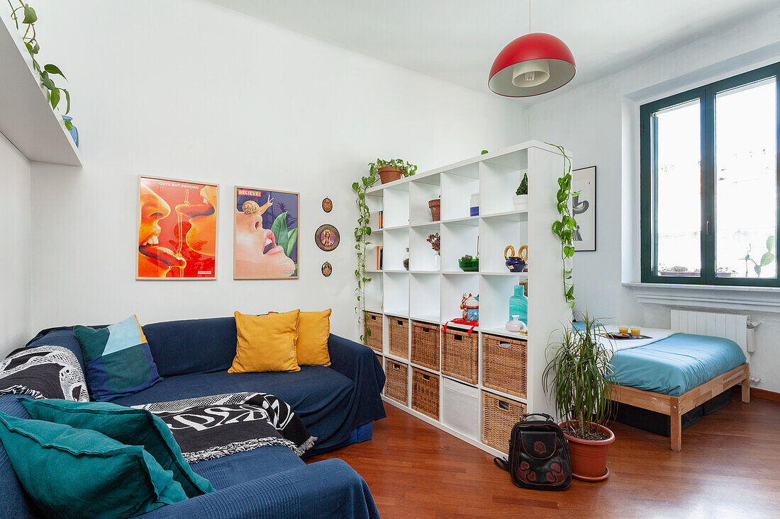 Bright living room with blue sofa, white shelves and houseplants
