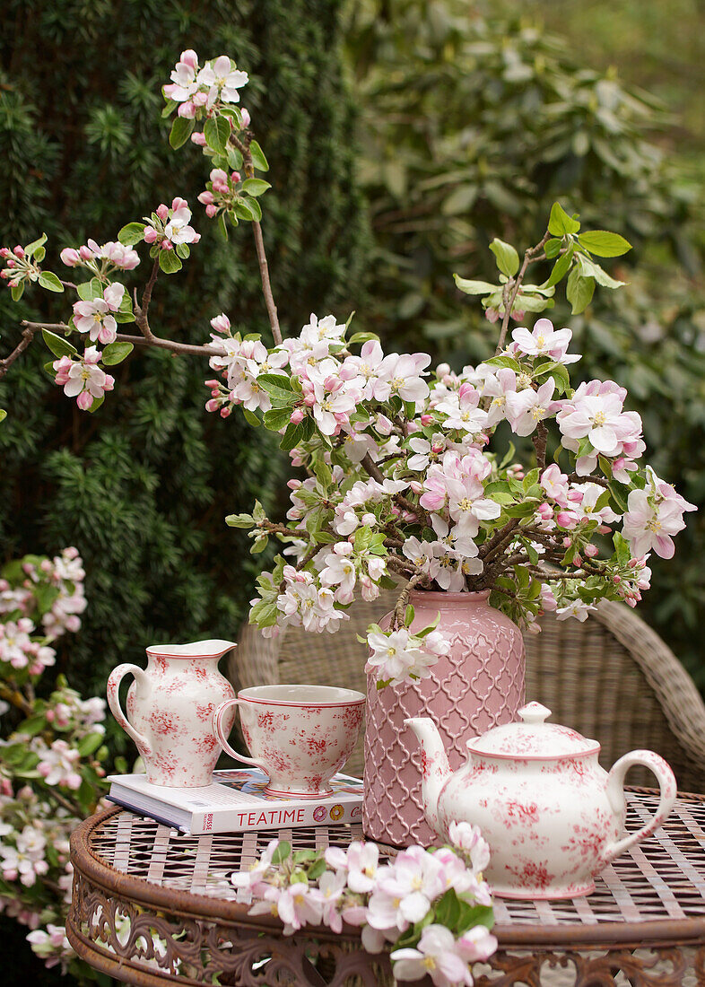Strauß aus Apfelblüten und Teegeschirr auf Gartentisch