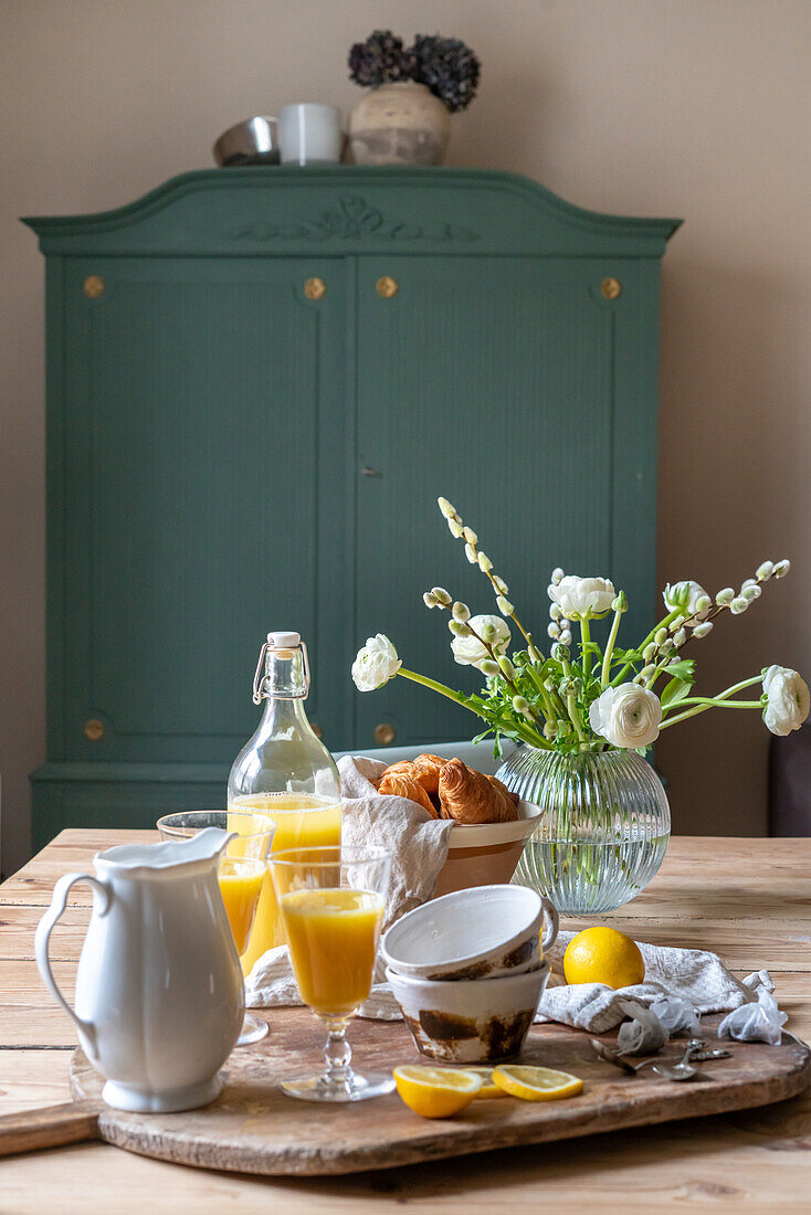 Frühstückstisch mit Croissants, Orangensaft und frischen Blumen