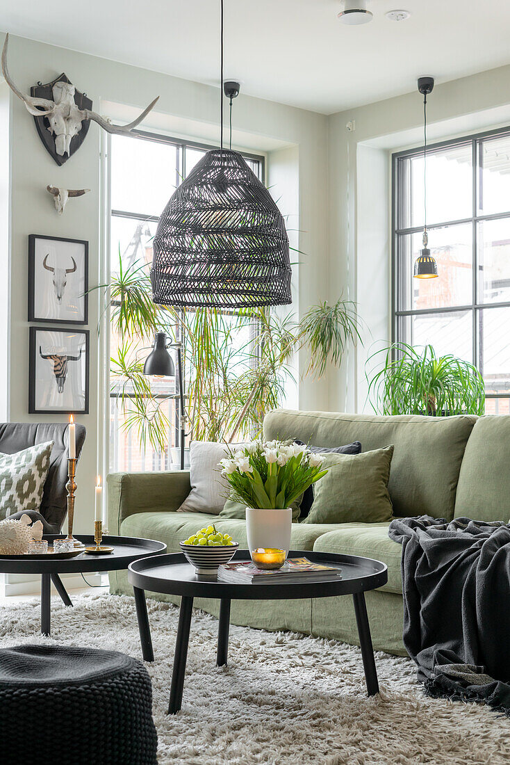 Bright living room with green sofa, rattan pendant light and indoor plants