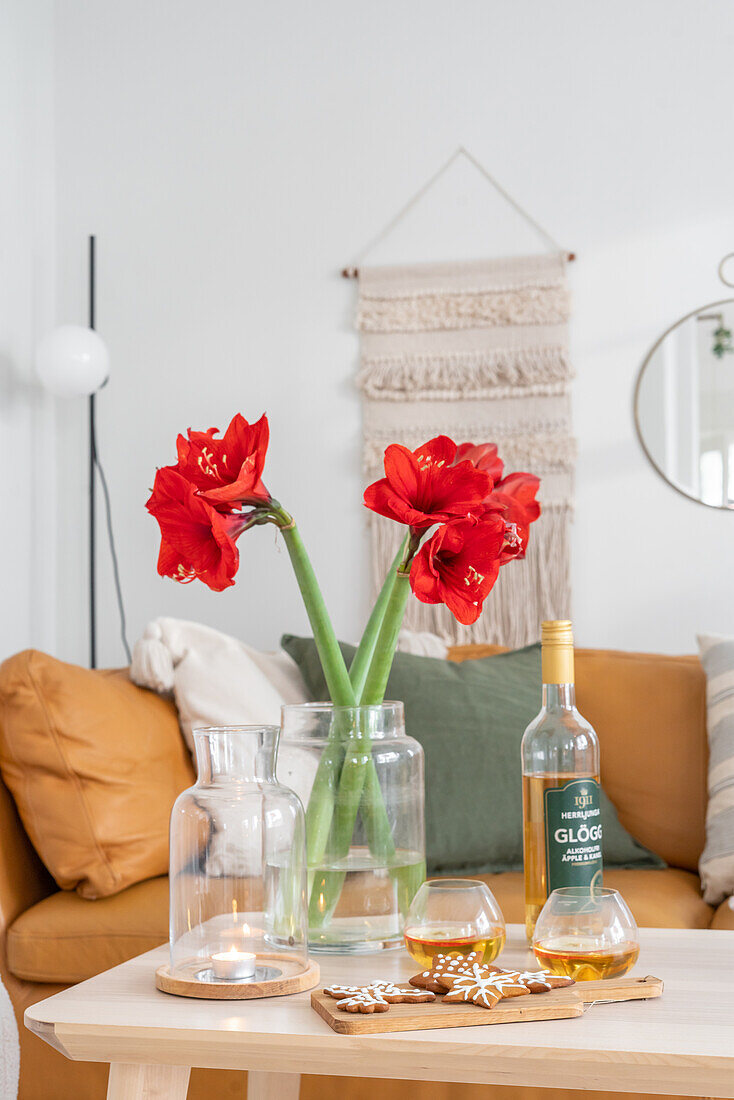 Amaryllis in Vase auf Holztisch mit Weihnachtsplätzchen und Getränken