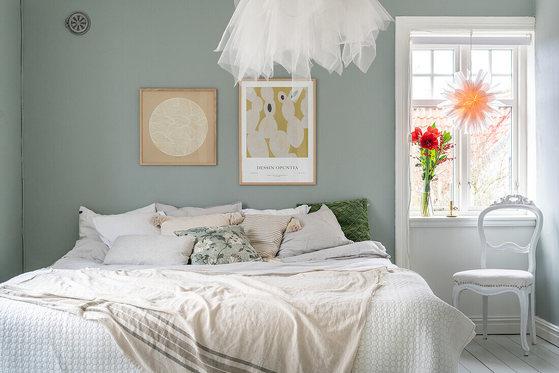 Brightly decorated bedroom with art on the wall and flowers on the windowsill