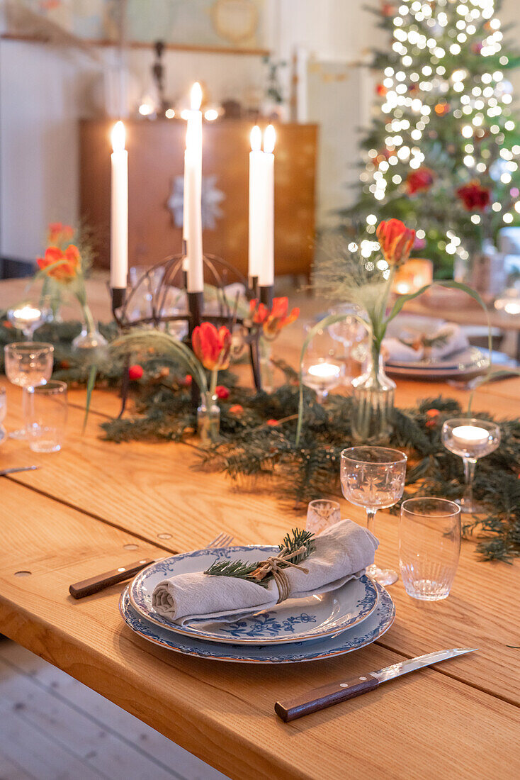 Festlich gedeckter Esstisch zu Weihnachten mit Tannenzweigen, Blumen und Kerzen