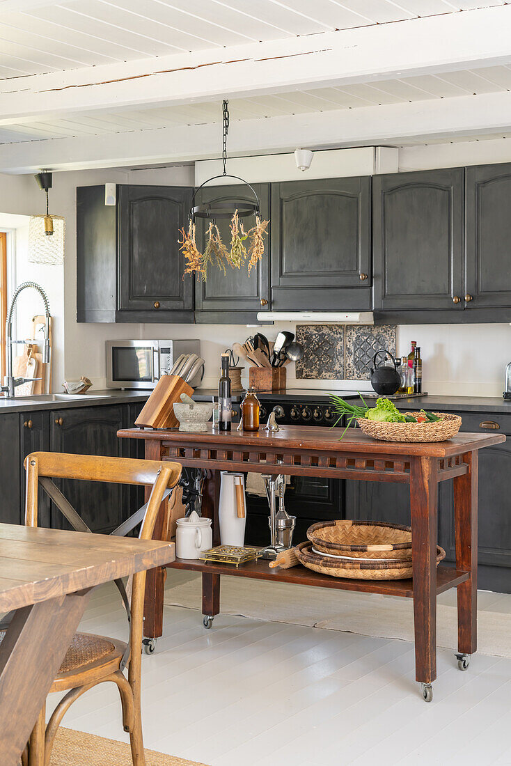 Country-style kitchen with dark cupboards and rustic wooden table