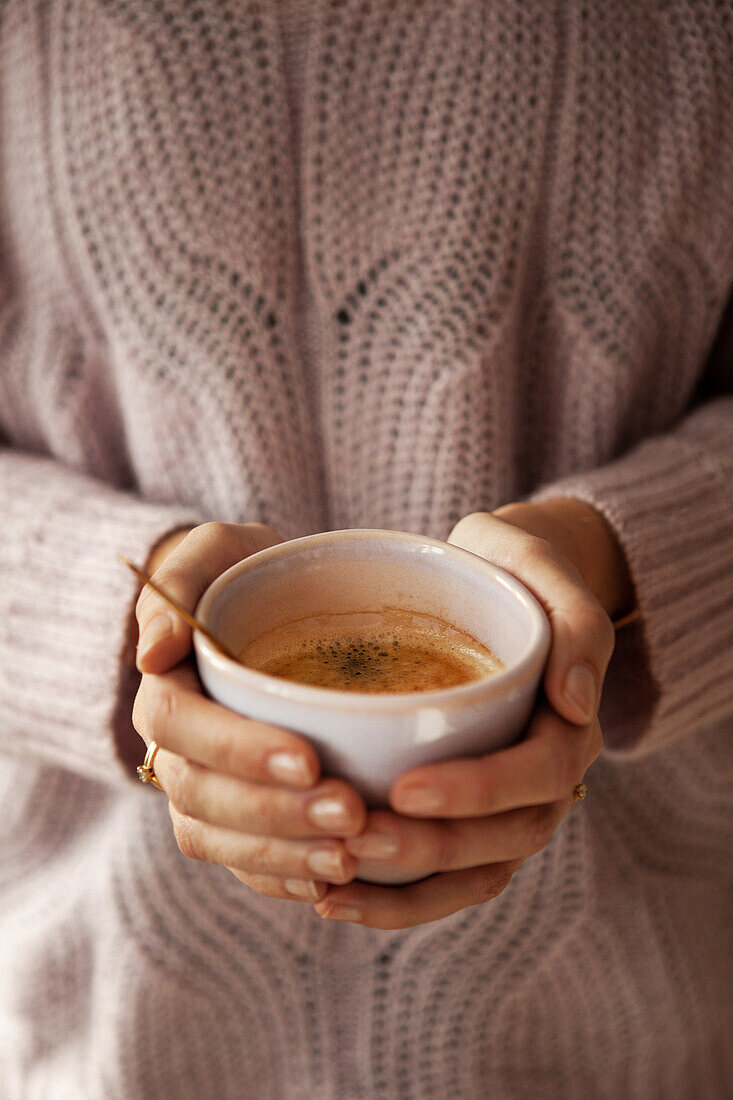 Person hält eine Tasse mit heißem Kaffee, Detailaufnahme mit Fokus auf den Händen