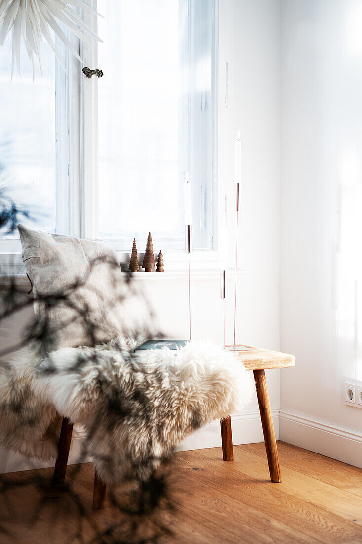 Wooden bench with pillow and fur in front of window