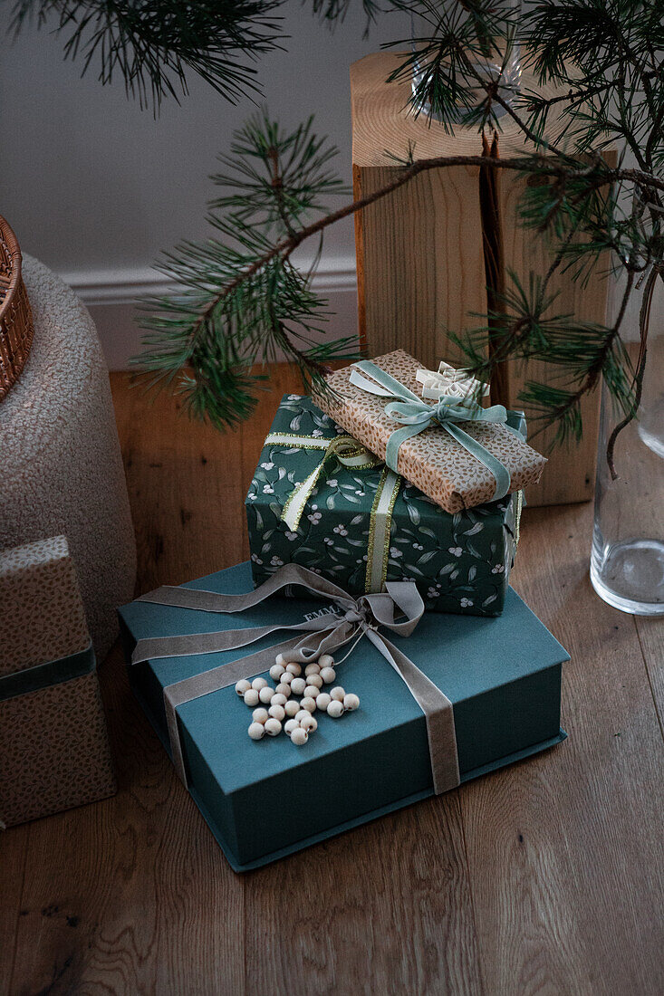 Christmas presents next to pine branches in a glass vase