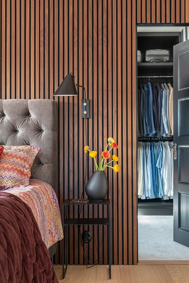 Bedroom with wooden wall, upholstered bed and walk-in wardrobe