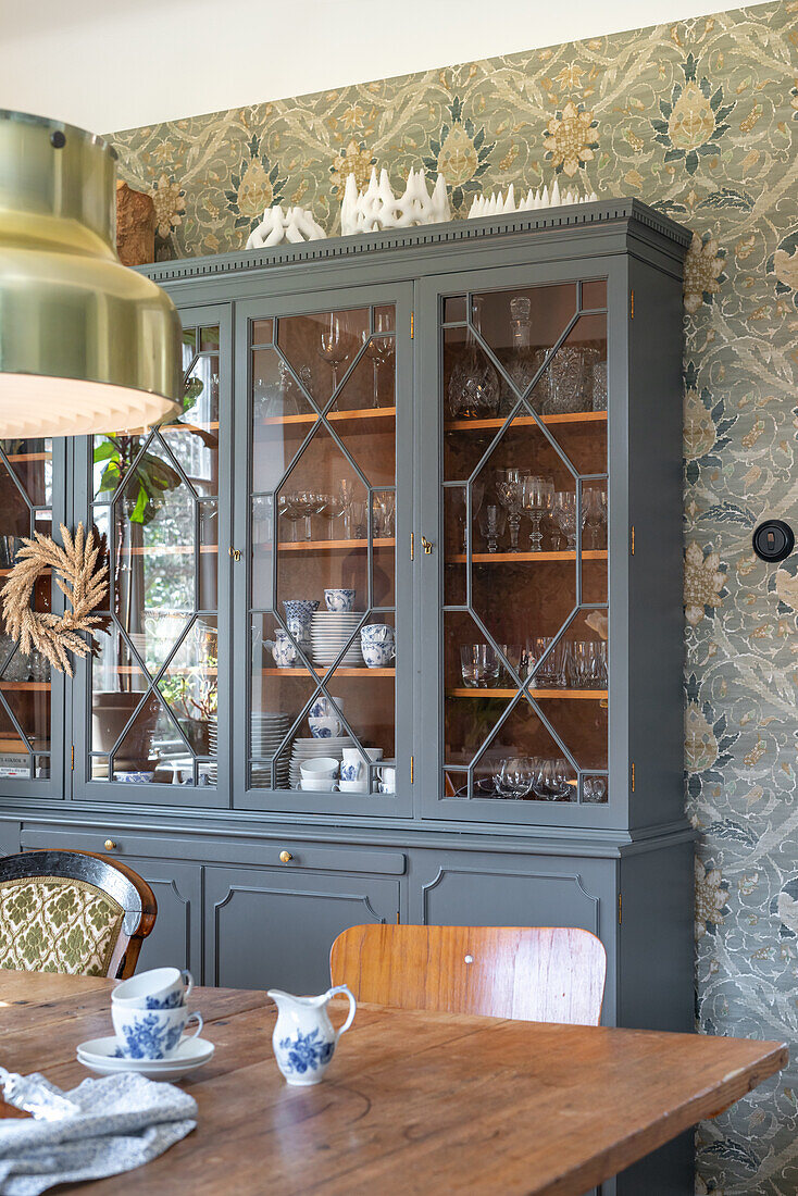 Display cabinet in the dining room with floral wallpaper and retro crockery