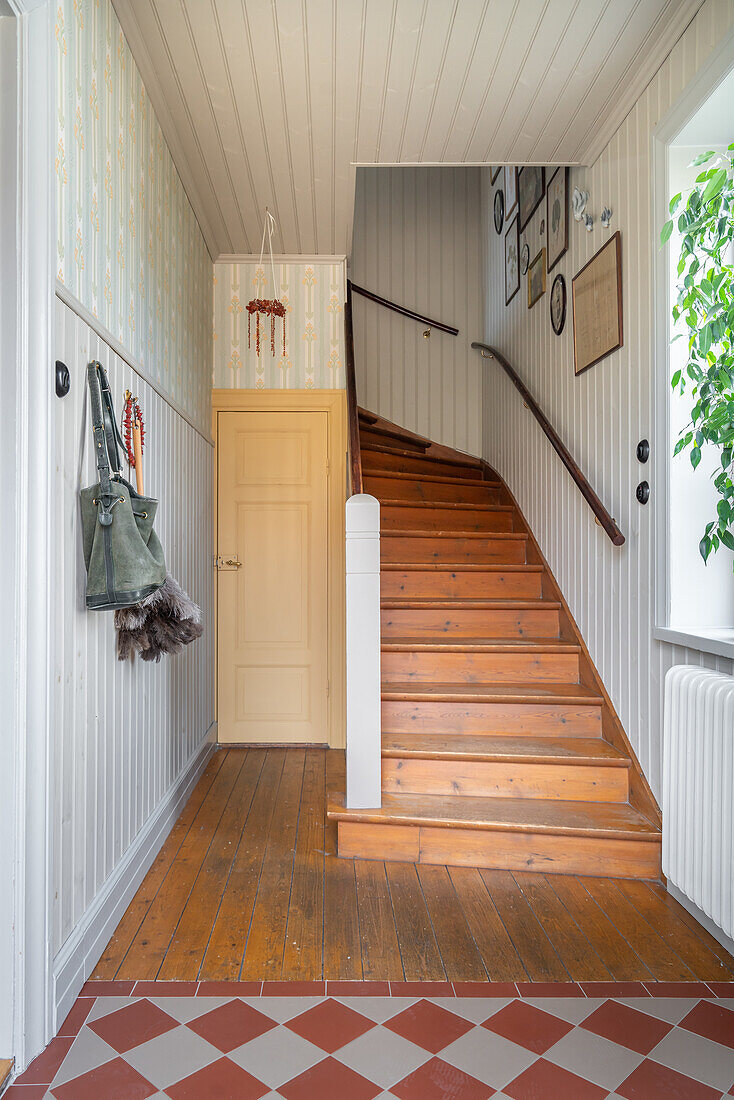 Wooden staircase, wooden floor and patterned tiles in the hallway