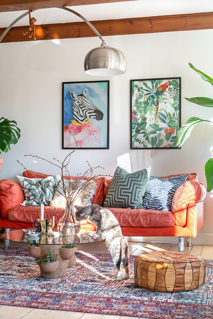 Wohnzimmer mit hellrotem Sofa, Kunstwerken und Katze