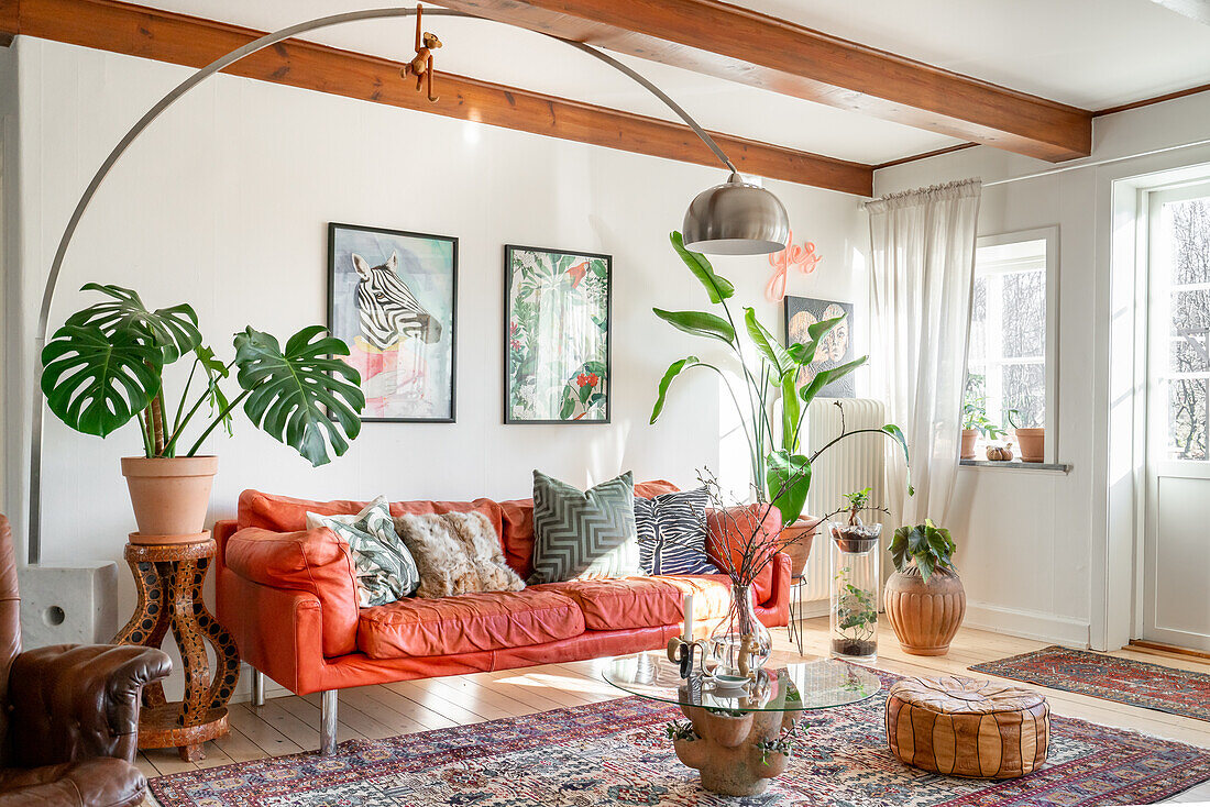 Living room with arc lamp, light red sofa and potted plants