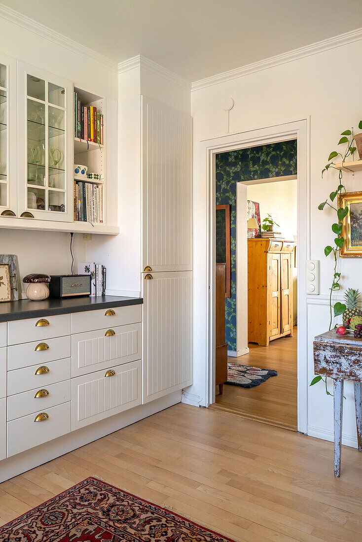 White kitchen with copper handles, passageway with view of hallway and living room