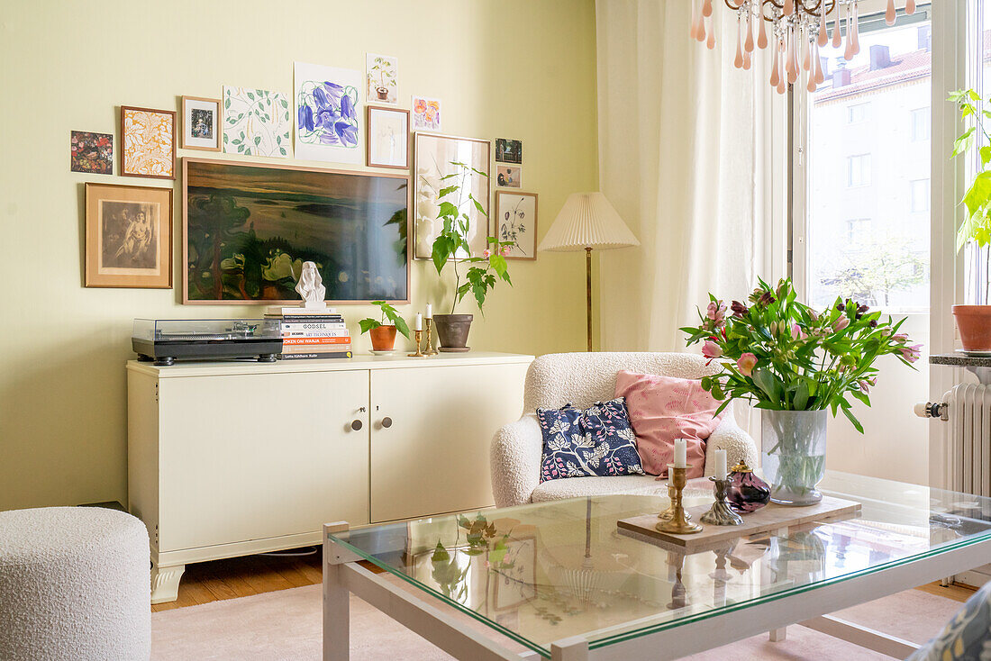 Living room with gallery wall, glass coffee table and bouquet of flowers