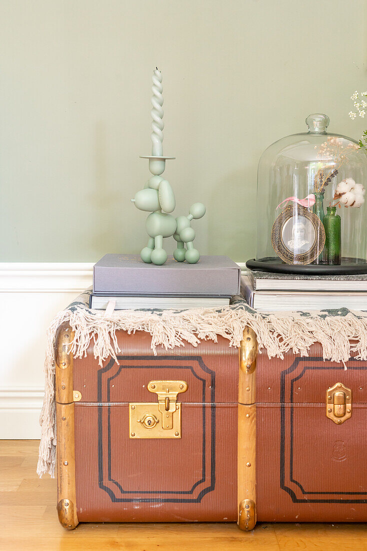 Vintage travelling suitcase as side table with decorative glass bell jar and candle