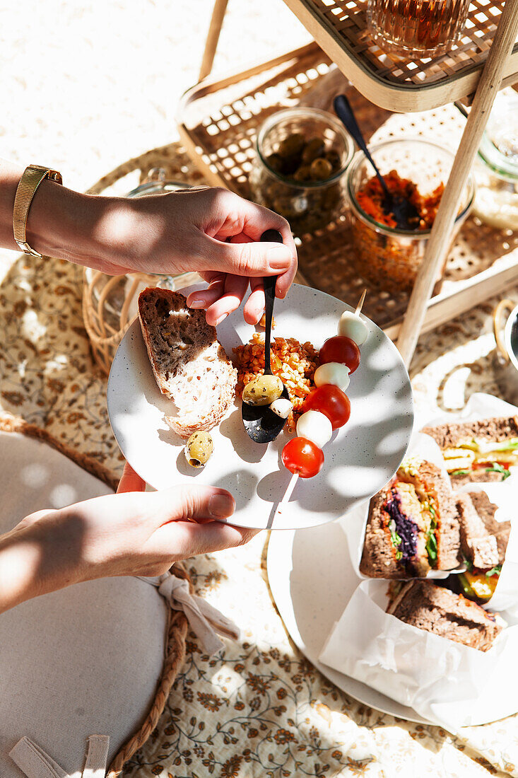 Sommerliche Picknick-Szene mit Antipasti und Sandwiches auf Picknickdecke