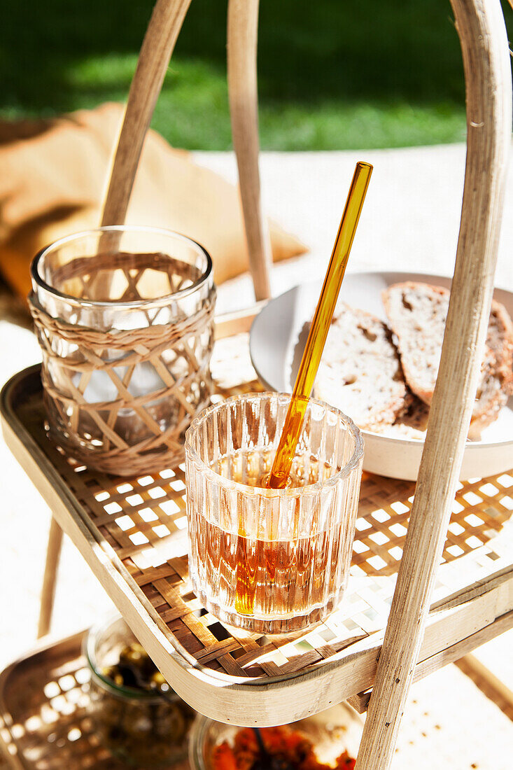 Getränk und Brotscheiben auf einem Rattan-Beistelltisch im Garten