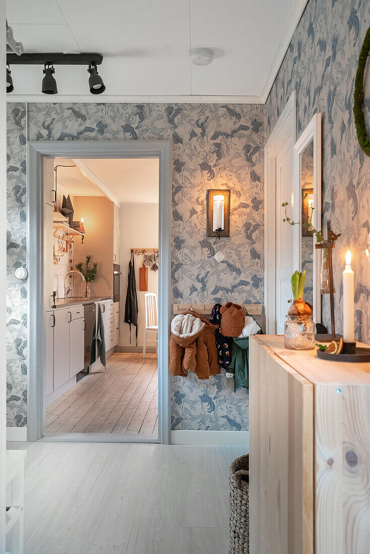 Hallway with patterned wallpaper and wooden elements, view into the kitchen