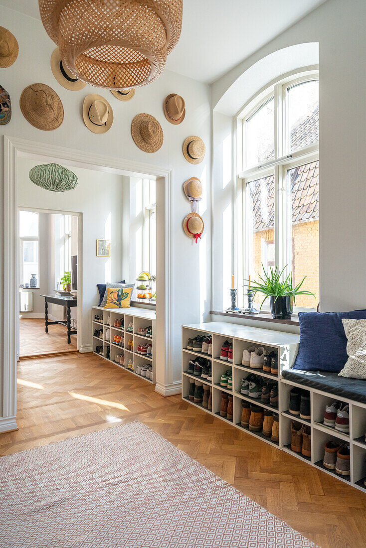 Hallway with shoe racks, seating and decorative hats on the wall