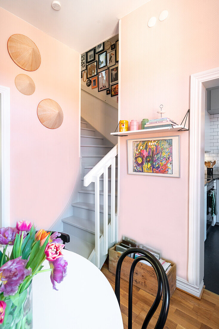 Hallway with pastel pink walls, staircase and wall decor