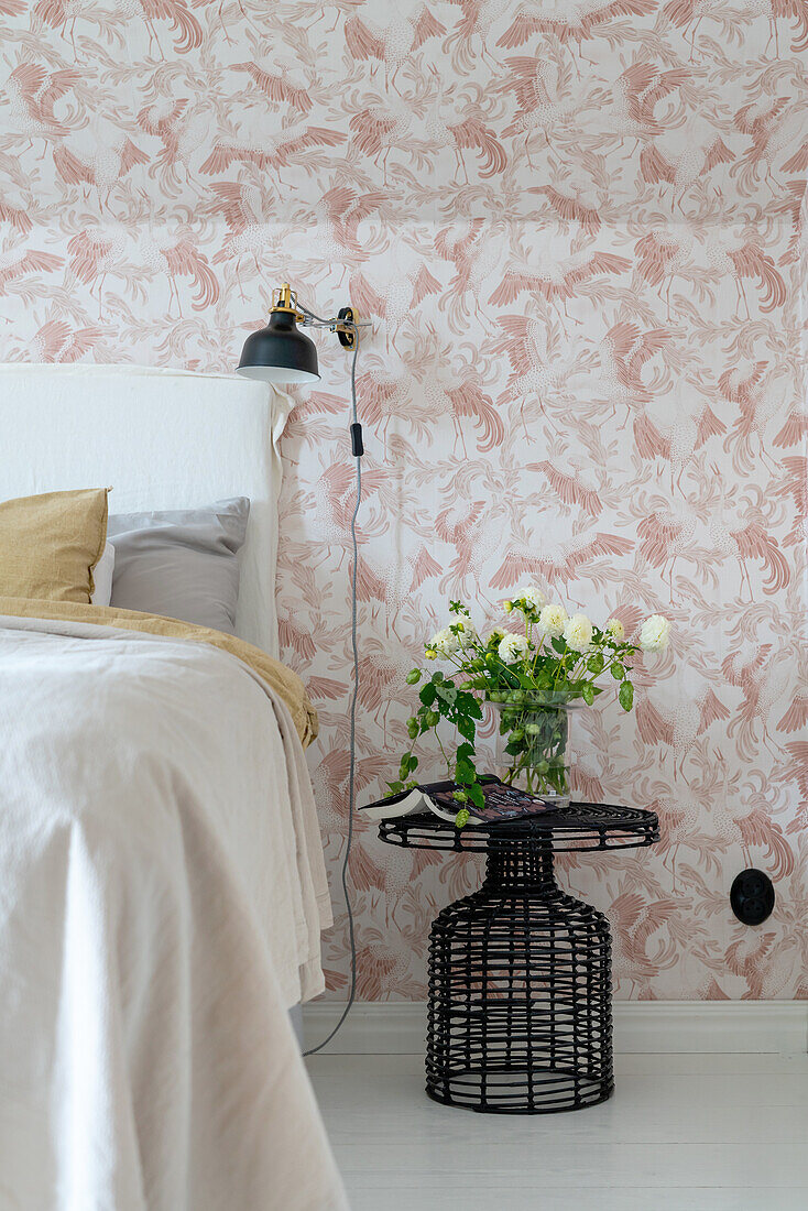 Bedroom with floral wallpaper and side table with bouquet of flowers