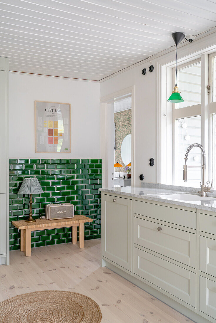 Kitchen with green metro tiles, white cabinets and a pendant light in green