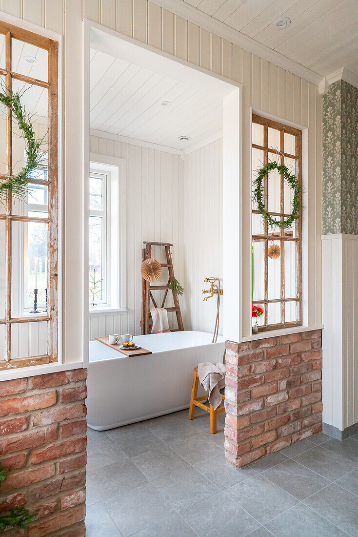 View of bathroom with bathtub and ladder, brick accents