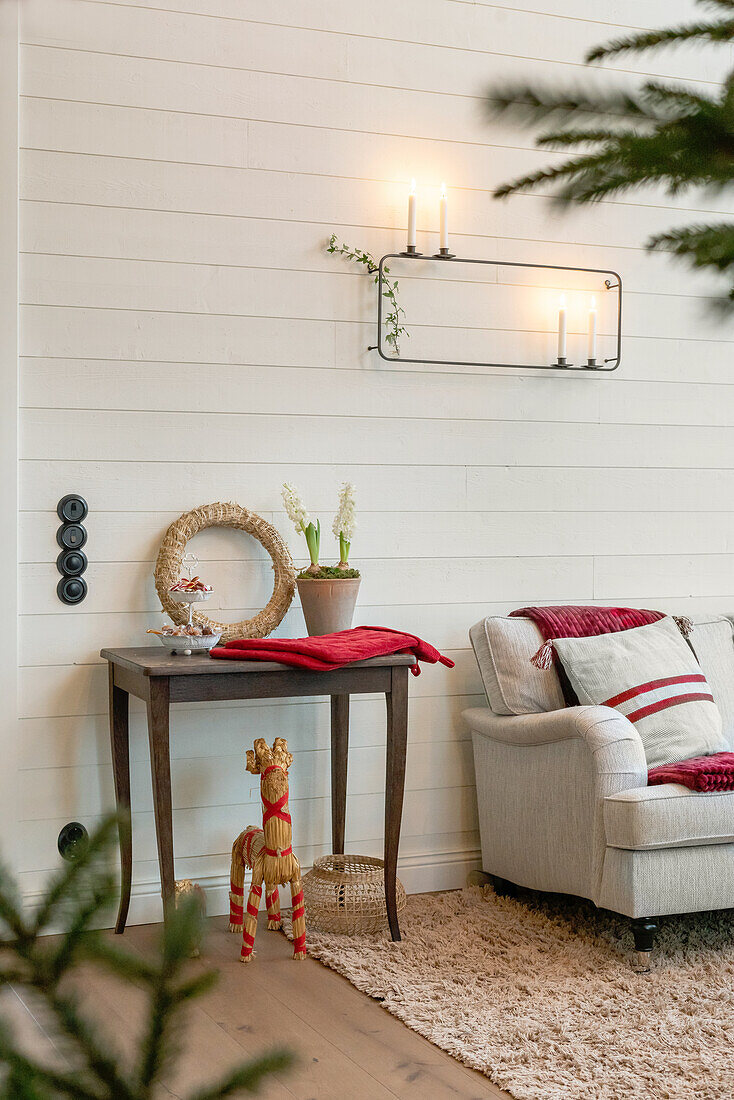 Side table with Christmas decorations, armchair and candle holder on the wall