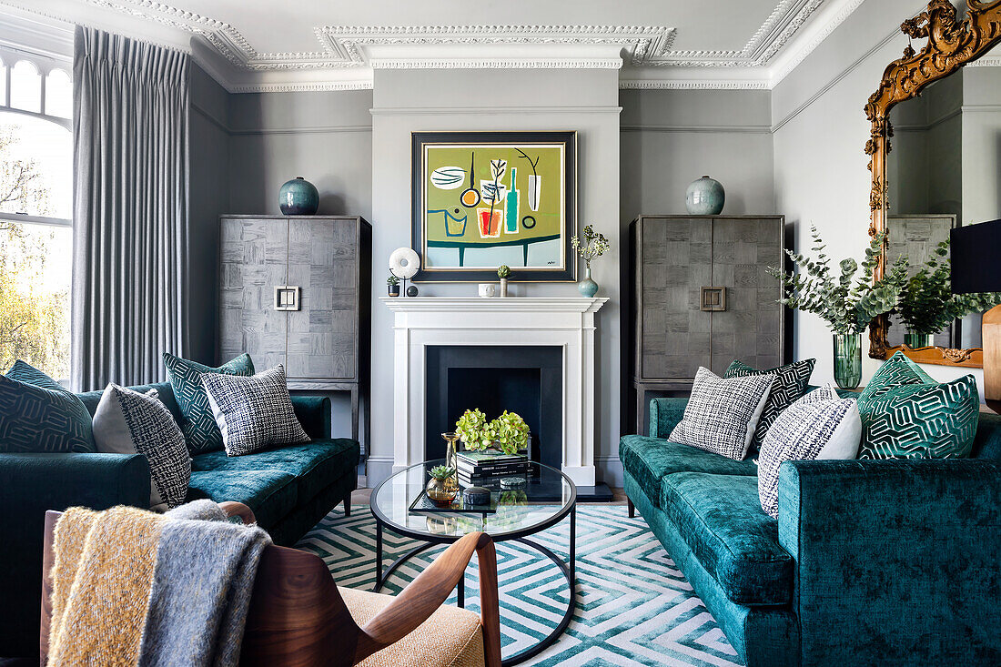 Velvet sofas, carpet with geometric pattern and classic fireplace in a living room