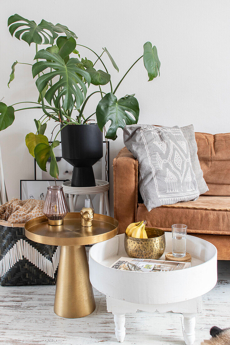 Monstera in black pot, couch and gold-coloured side table