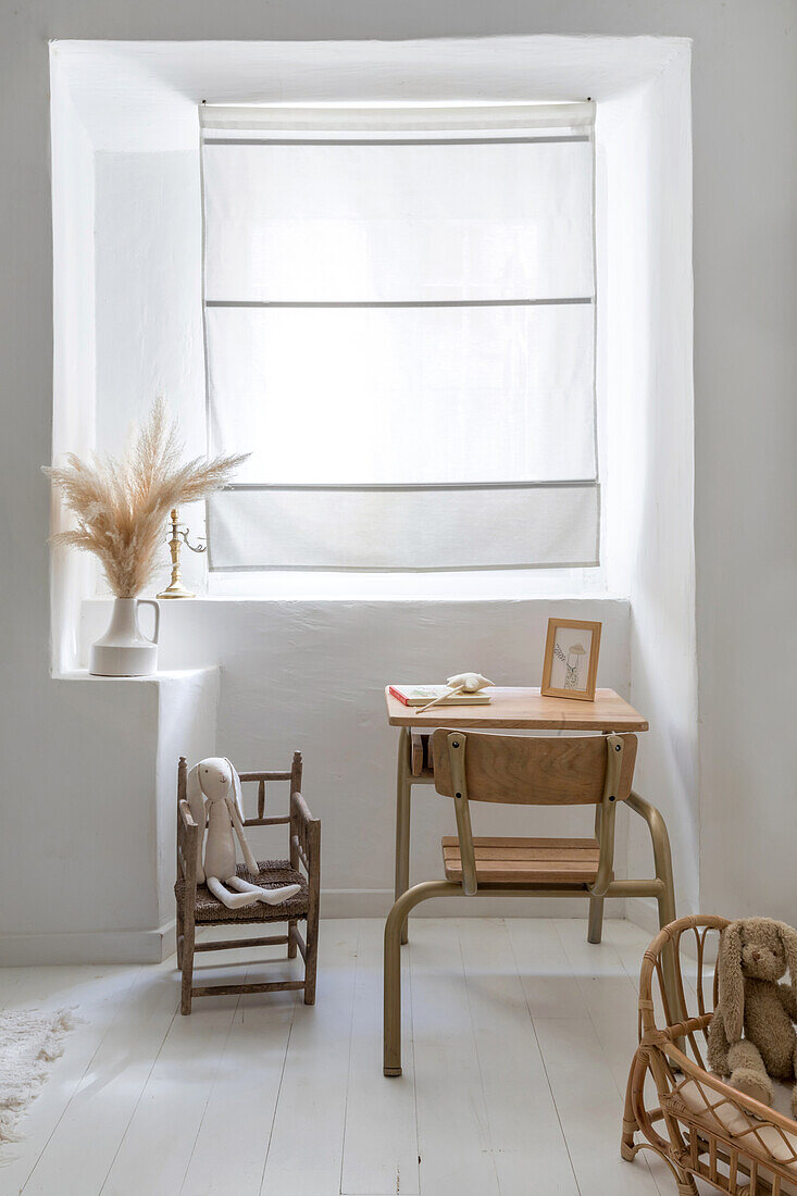 Children's table with wooden chair in front of window