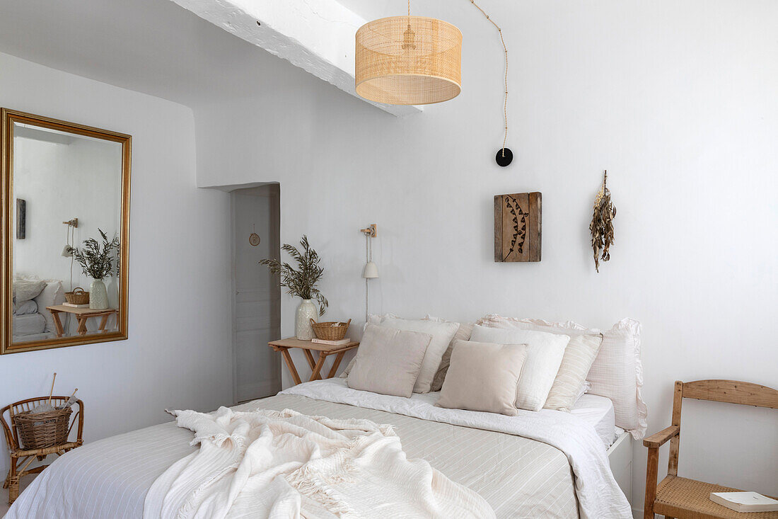 Light-coloured bedroom with white bed linen and wooden furniture