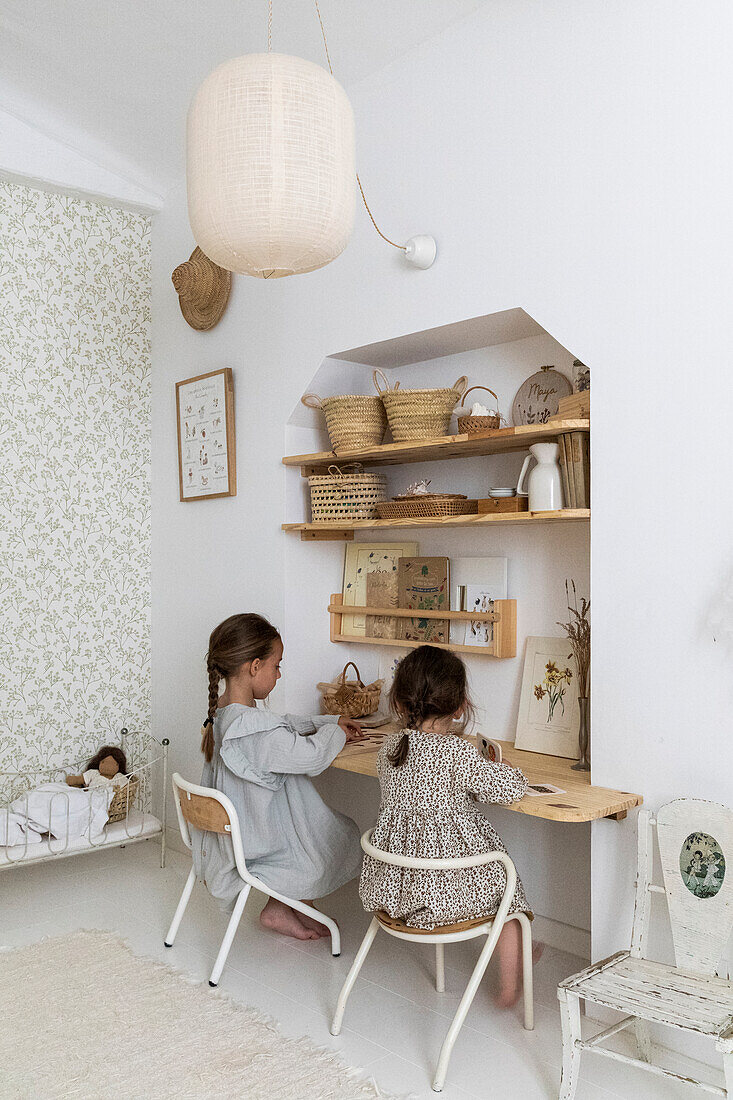 Kinder spielen in einem hellen Kinderzimmer am Schreibtisch