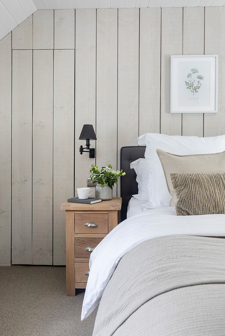 Bright bedroom with wooden wall paneling and bedside table