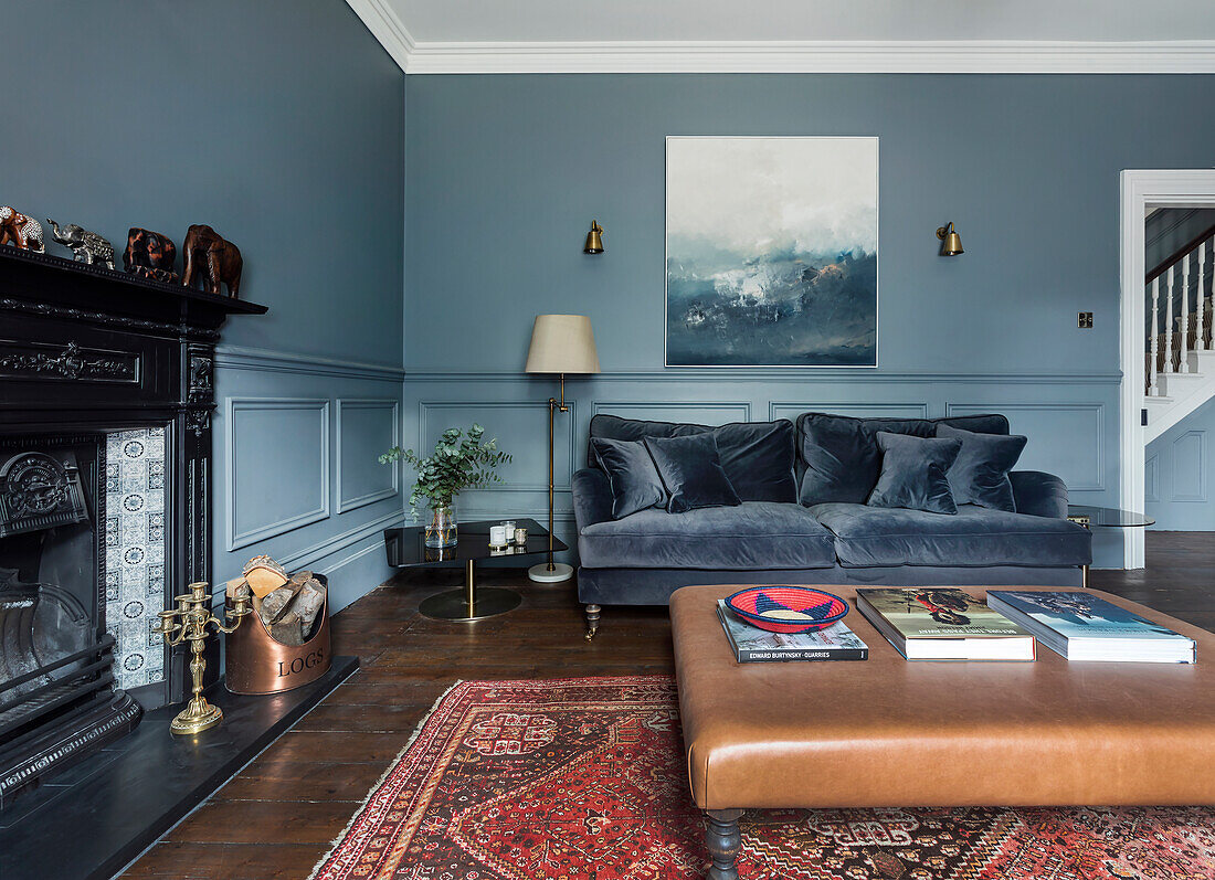 Blue living room with velvet sofa, fireplace and leather table