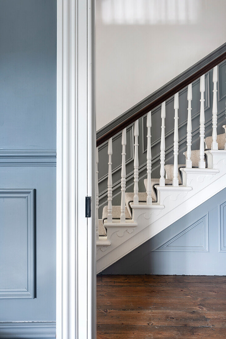 Staircase with white balusters and blue wall panels