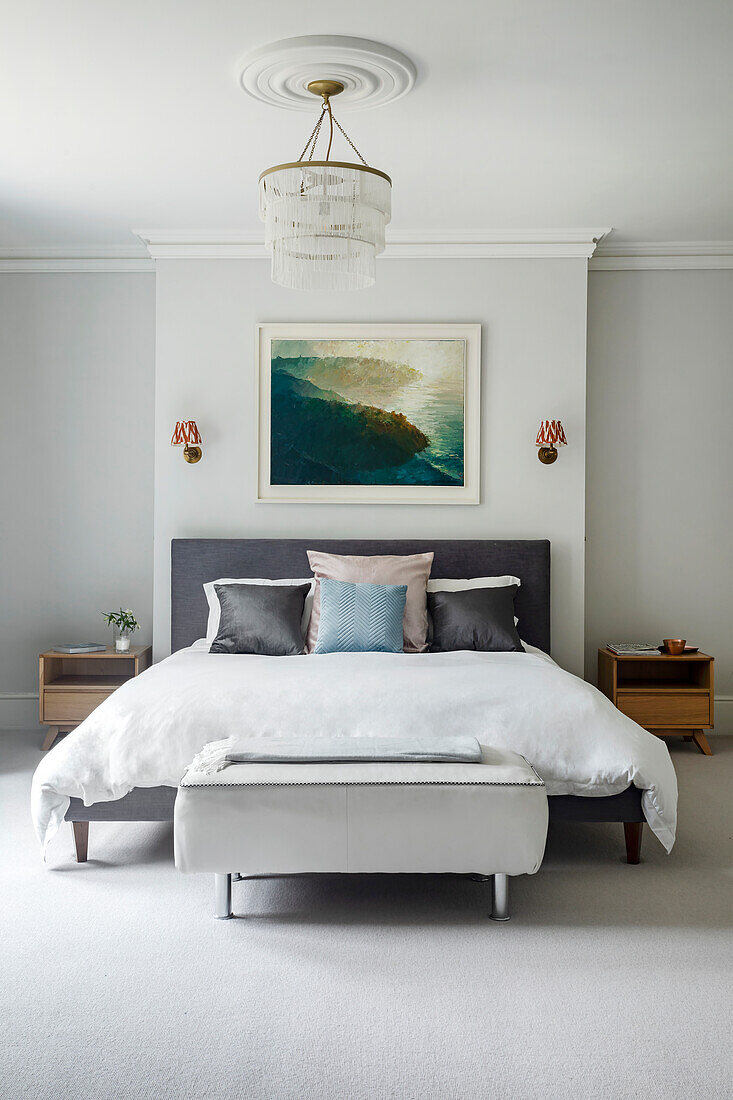 Bedroom with white bed linen, grey headboard and artwork above the bed