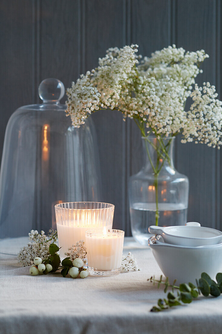 Stylish table decoration with flowers, candles, bowls, cloche vases and eucalyptus
